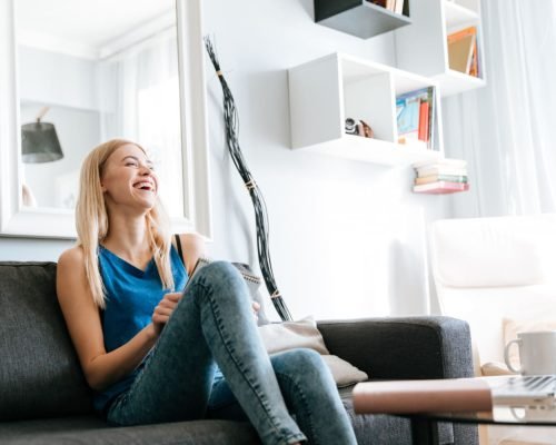 cheerful-woman-sitting-laughing-sofa-home