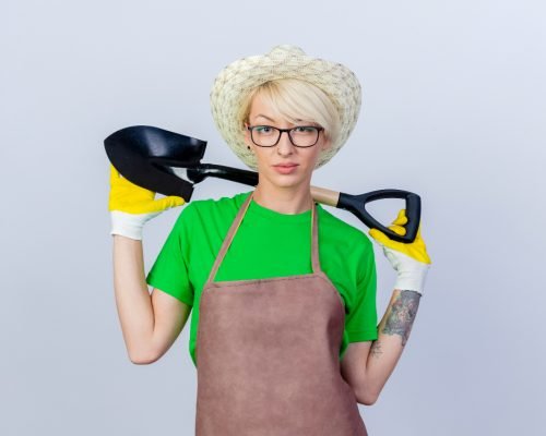 young-gardener-woman-with-short-hair-apron-hat-holding-shovel-with-serious-confident-expression